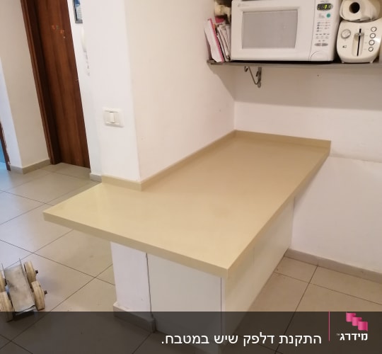 משטח שיש בהיר במטבח עם מיקרוגל מעליו